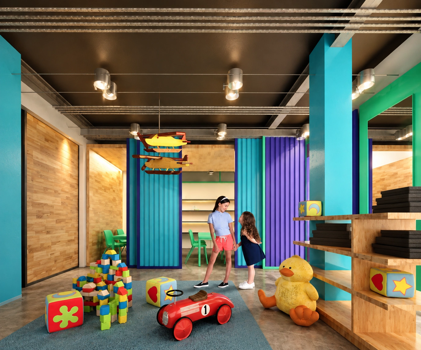 Espacio infantil con juguetes, divisiones de colores y niñas jugando