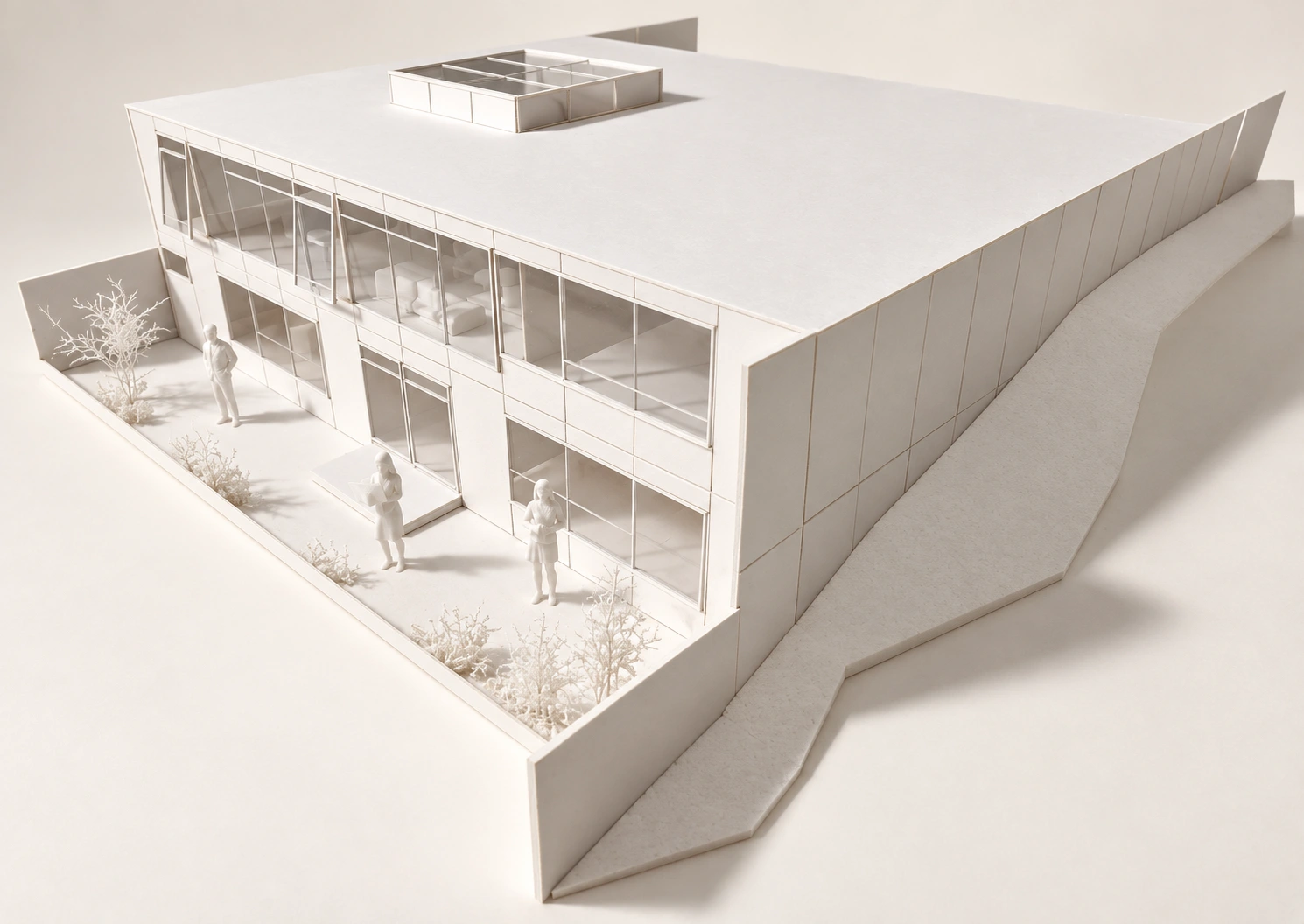 Maqueta blanca de un edificio de dos niveles con fachada acristalada, patio y lucernario